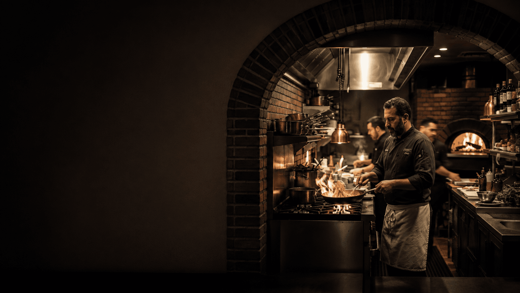 Kocken lagar mat över öppen låga i Osterias kök